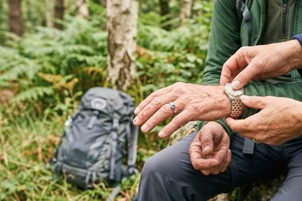 les mains d'une personne retirant doucement une montre en m&eacute;tal et des bagues du poignet d'une victime.