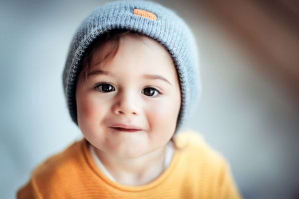 un bébé garçon avec des yeux noirs et cheveux bruns portant un bonnet