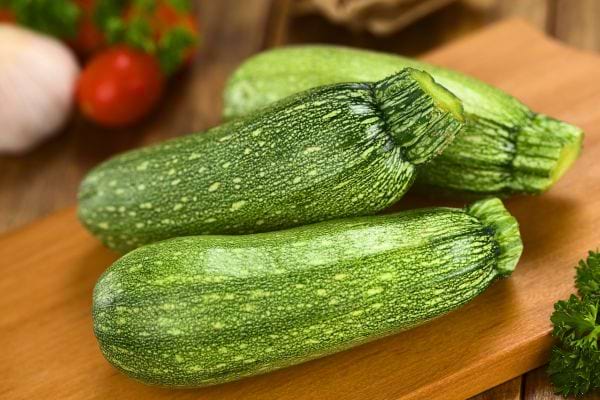 des courgettes posées sur une table avec des tomates et de l'ail