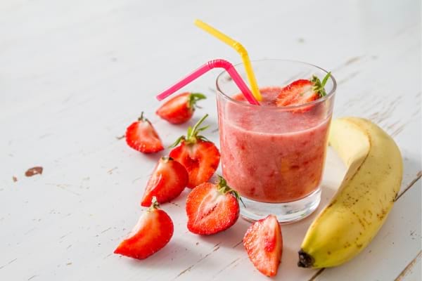 Jus à la fraise et à la banane servi avec des fruits frais.