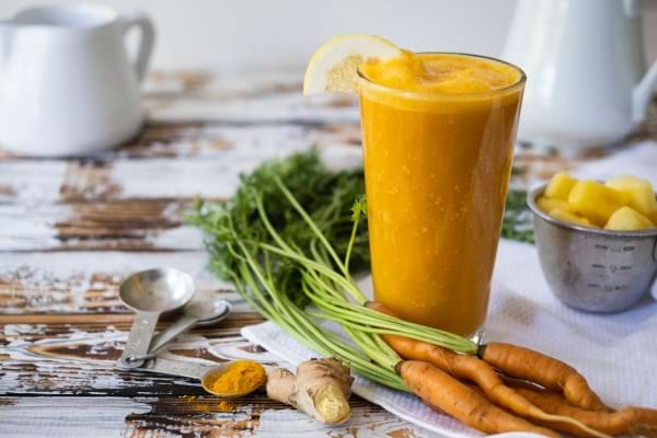 Jus de carotte, mangue, gingembre et curcuma servi dans un verre