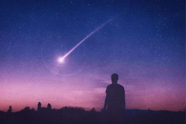 un ciel bleu avec des reflets roses avec des étoiles, une étoile filante, un homme qui regarde