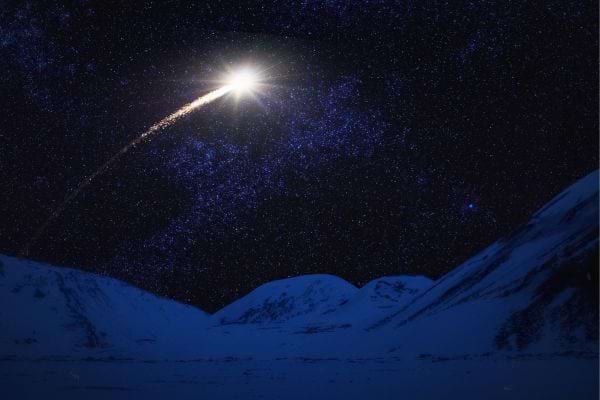 un ciel obscure avec des étoiles et une étoile filante et des montagnes en fond