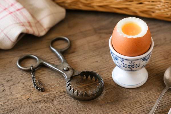 pince ancienne à couper les oeufs coques à côté d'un oeuf ouvert