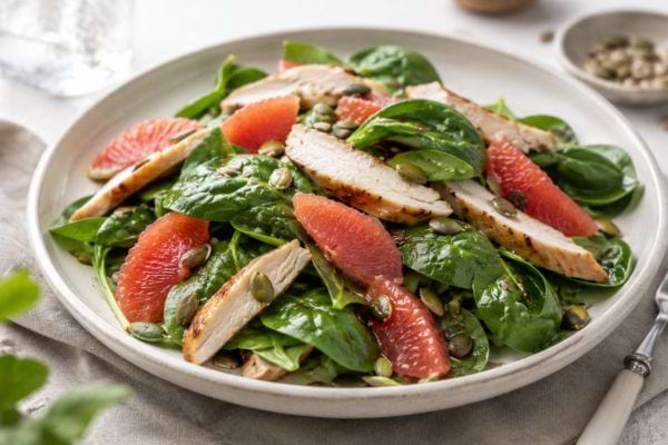salade épinards pamplemousse poulet dans une assiette blanche