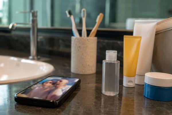 Produits de toilette et flacon intime posés près d’un téléphone sur le lavabo d’une chambre d’hôtel.