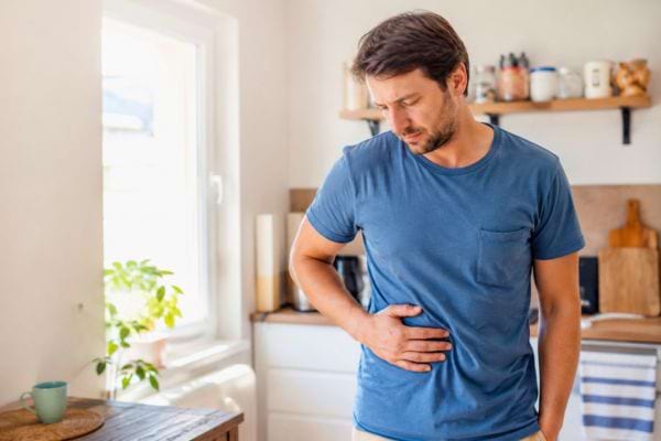 Homme tenant son foie avec une douleur abdominale dans une cuisine
