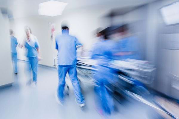 des infirmiers poussent un brancard dans un couloir avec impression de vitesse
