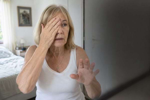 Femme couvrant un &oelig;il face &agrave; une zone sombre, signe possible d&rsquo;une perte brutale de vision.