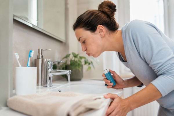 Femme se rinçant la bouche avec un bain de bouche pour soulager un muguet buccal.