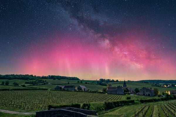 a spectacular pink and magenta aurora borealis glowing softly above the horizon