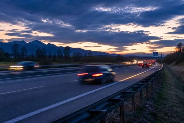 une autoroute européenne au crépuscule avec des phares de voitures floutés par le mouvemen