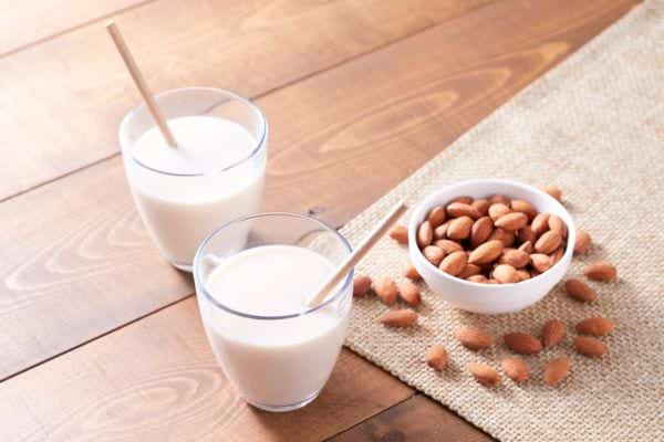 amandes dans une coupelle à côté de deux verres de lait