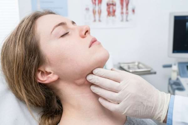 un m&eacute;decin examinant d&eacute;licatement le cou gonfl&eacute; d'une patiente