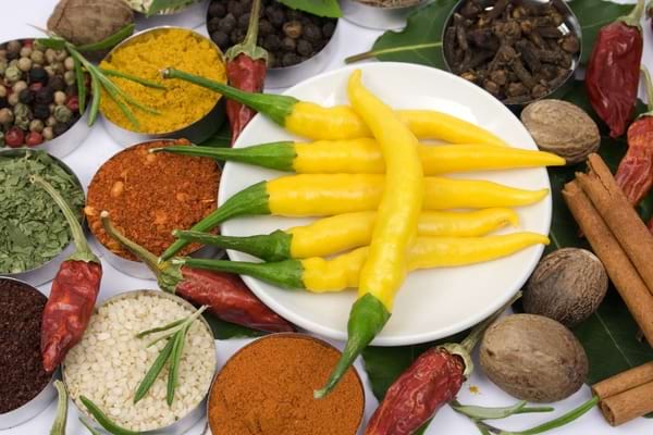 Piments jaunes et rouges entourés de cannelle et de différentes épices.