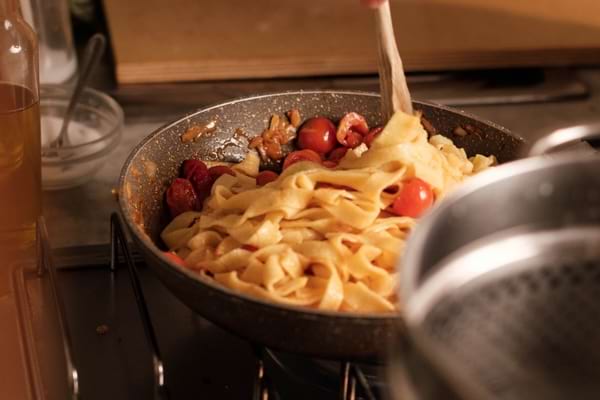 Tagliatelles aux tomates remuées dans une poêle pendant la cuisson sur le feu.