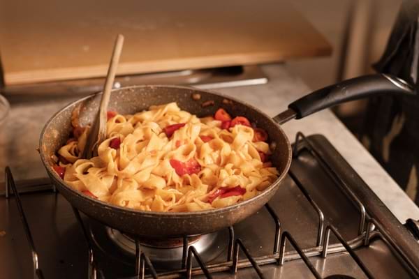 Tagliatelles aux tomates cuisant directement dans une poêle sur le feu.