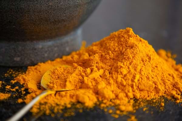 du curry en poudre sur une table avec une cuillère argentée