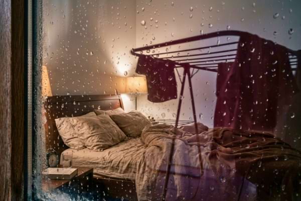 une chambre à coucher cosy avec un lit défait proche d'Un étendoir à linge