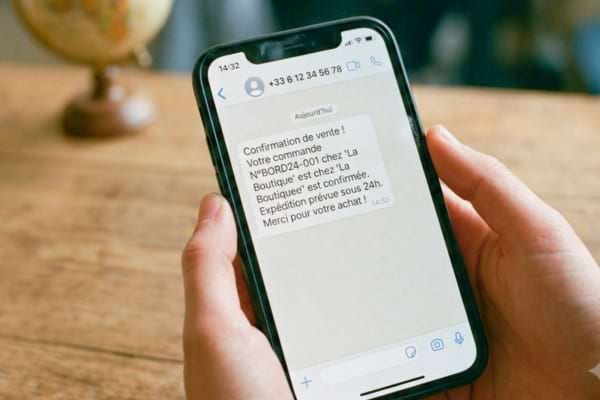un écran de téléphone affichant un SMS de confirmation de vente provenant d'un numéro classique