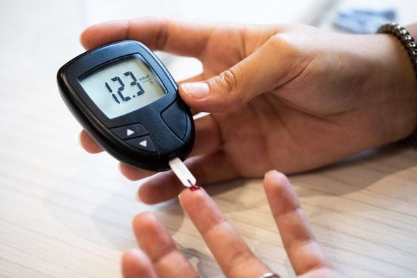 Mesure de la glycémie avec un lecteur affichant un taux de sucre sanguin de 12,3 mmol/L