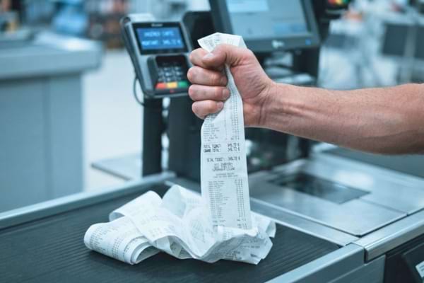 Un homme serrant un ticket de caisse à cause des prix trop chers