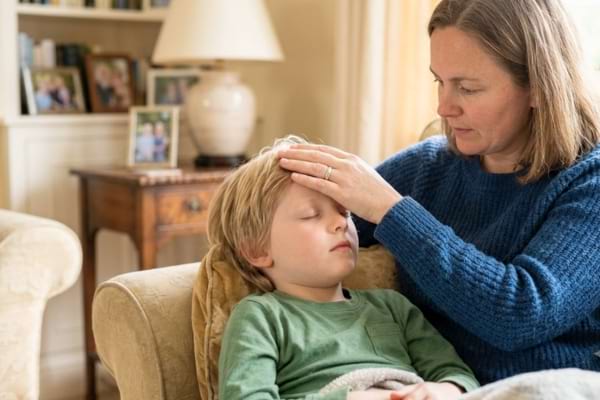 une mère posant doucement le dos de sa main sur le front de son enfant