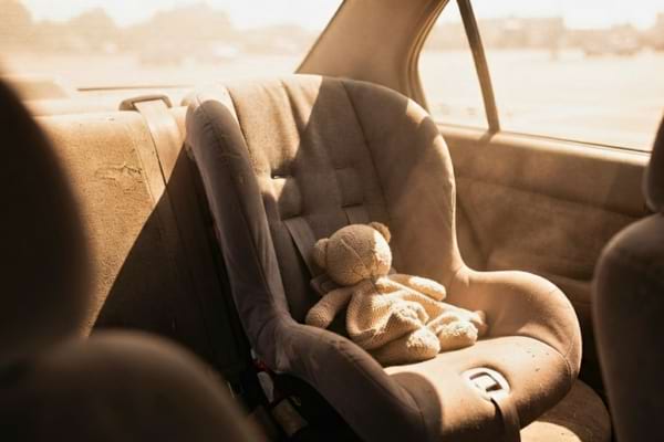 un siège auto pour bébé vide dans une voiture baignée d'une lumière solaire intense, un petit doudou