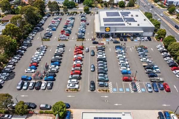 A busy supermarket parking lot completely full of cars, overhead drone shot