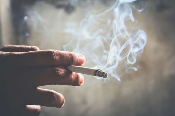 Une main tenant une cigarette entre ses doigts
