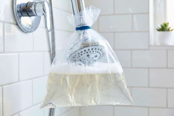 Un pommeau de douche en m&eacute;tal chrom&eacute; trempant &agrave; l'int&eacute;rieur d'un sac en plastique 