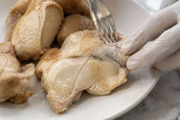 Inspection de la texture et de la couleur de morceaux de poulet cuit.