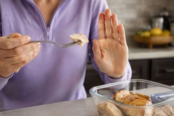 Personne refusant de go&ucirc;ter un morceau de poulet cuit qui semble douteux.
