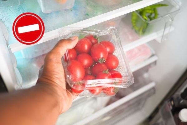 personne qui met une barquette de tomate cerise au frigo