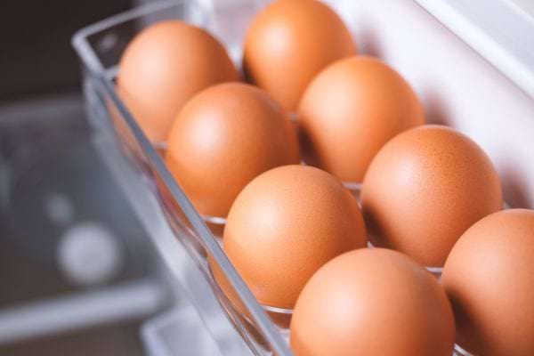 des oeufs frais ou durs rangés dans la porte du frigo dans un porte oeuf intégré