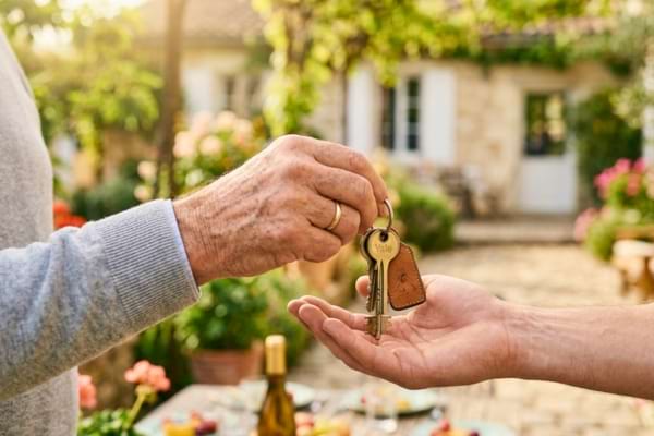 mains âgées remettant un trousseau de clés de maison à des mains plus jeunes