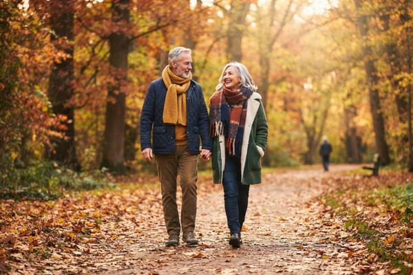 un couple de retraités actifs et en bonne santé, marchant dans un parc en automne