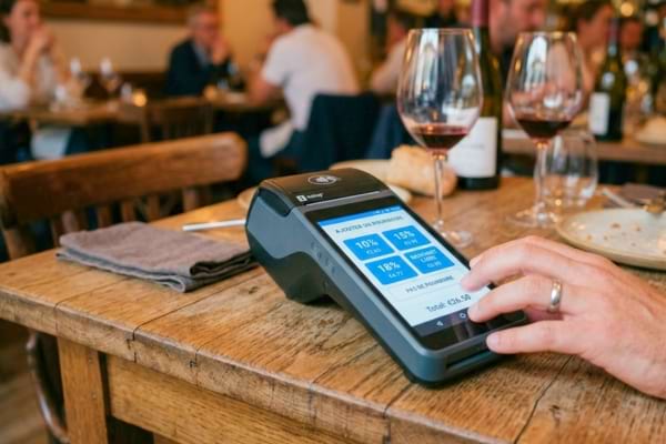 un terminal de paiement moderne posé sur une table de restaurant en bois