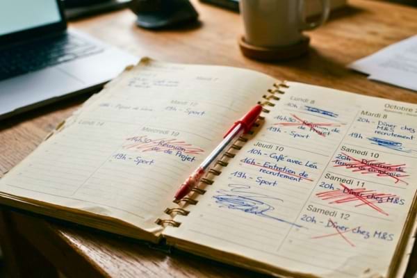 un agenda papier avec plusieurs rendez-vous raturés au stylo rouge