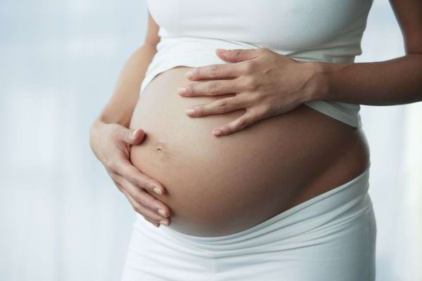 gros. plan sur le ventre d'une femme enceinte habill&eacute;e en blanc