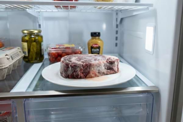  plate with a frozen steak slowly thawing inside a clean,