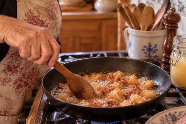 une femme qui fait cuire des aliments à la graisse d'oie dans une poele