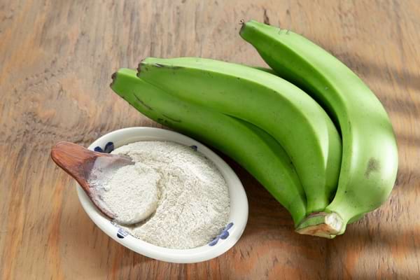 Bananes vertes accompagnées d’un bol de farine de banane.