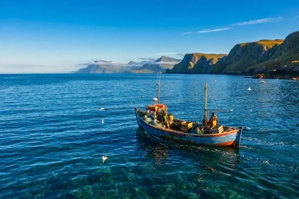 un petit bateau de pêche artisanale naviguant sur une mer d'un bleu profond