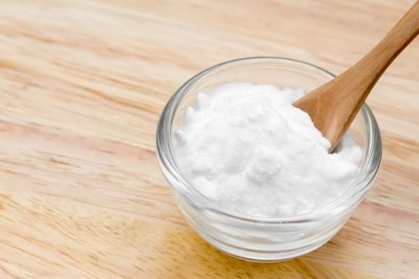 Cuillère de bicarbonate dans un bol rempli de bicarbonate sur une table en bois