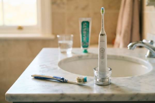 une brosse &agrave; dents manuelle usag&eacute;e pos&eacute;e &agrave; c&ocirc;t&eacute; d'une brosse &agrave; dents &eacute;lectrique moderne