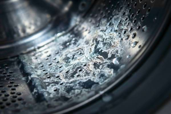 un tambour de machine à laver en acier inoxydable, montrant des traces blanches de calcaire