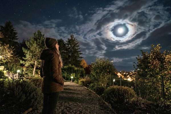 femme qui contemple la lune dans les nuages avec une forme d'oeil