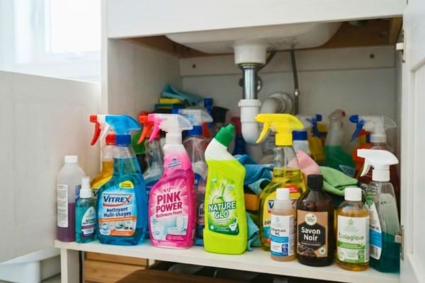 lavabo encombré par de nombreuses bouteilles de produits d'entretien chimiques
