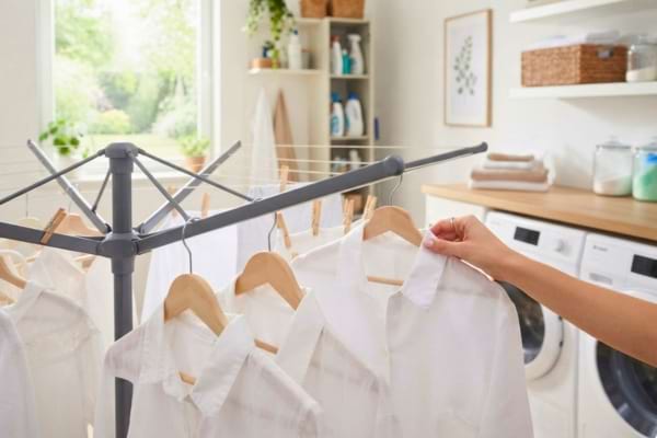 bras en acier d'un s&eacute;choir parapluie moderne, des cintres avec des chemises blanches y sont accroch&eacute;s